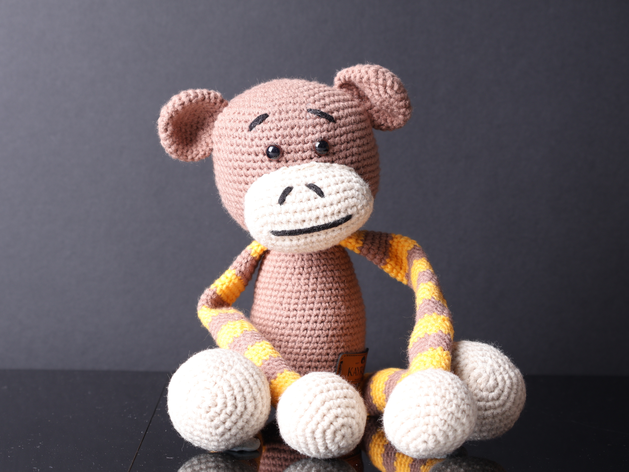 Handmade amigurumi monkey toy with extra-long arms, ideal for baby room decor or as a curtain tie-back holder. Crafted with soft yarn in shades of brown and beige, with embroidered eyes and a friendly smile